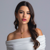 Woman wearing a gold sphere pendant necklace with matching gold earrings and rings, styled in an off-shoulder white top against a grey background.