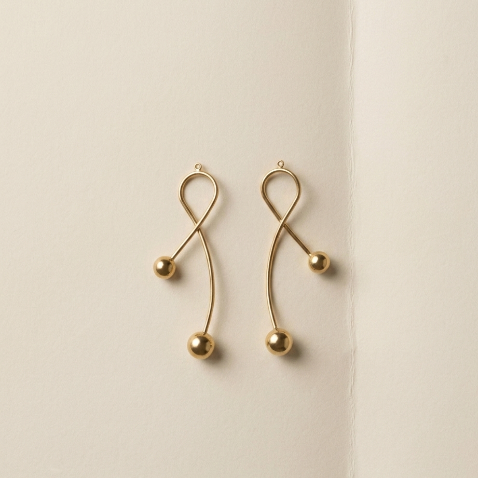 Curved middle components of the ELAI modular gold earrings shown separately