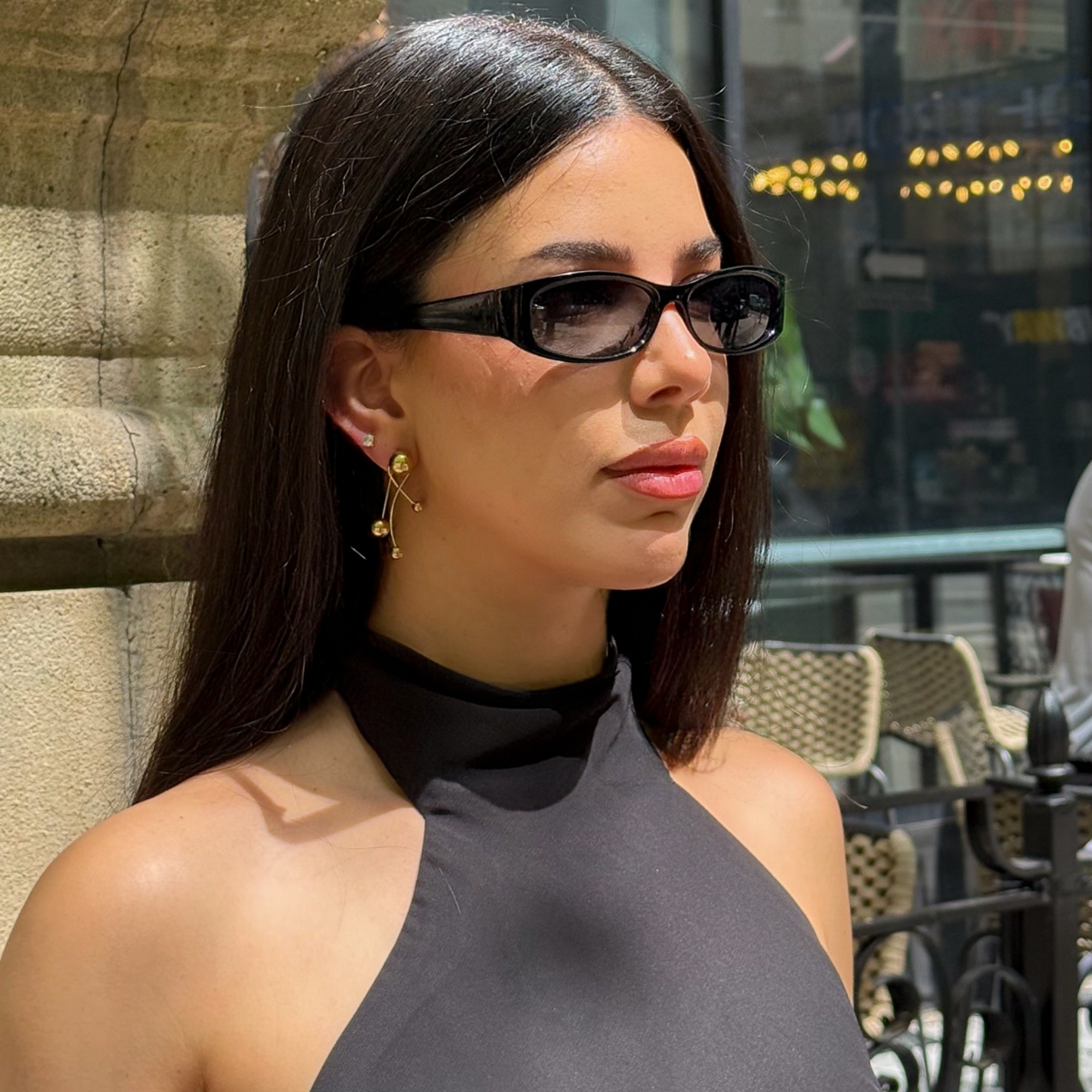ELAI gold earrings worn with a black halter top and sunglasses