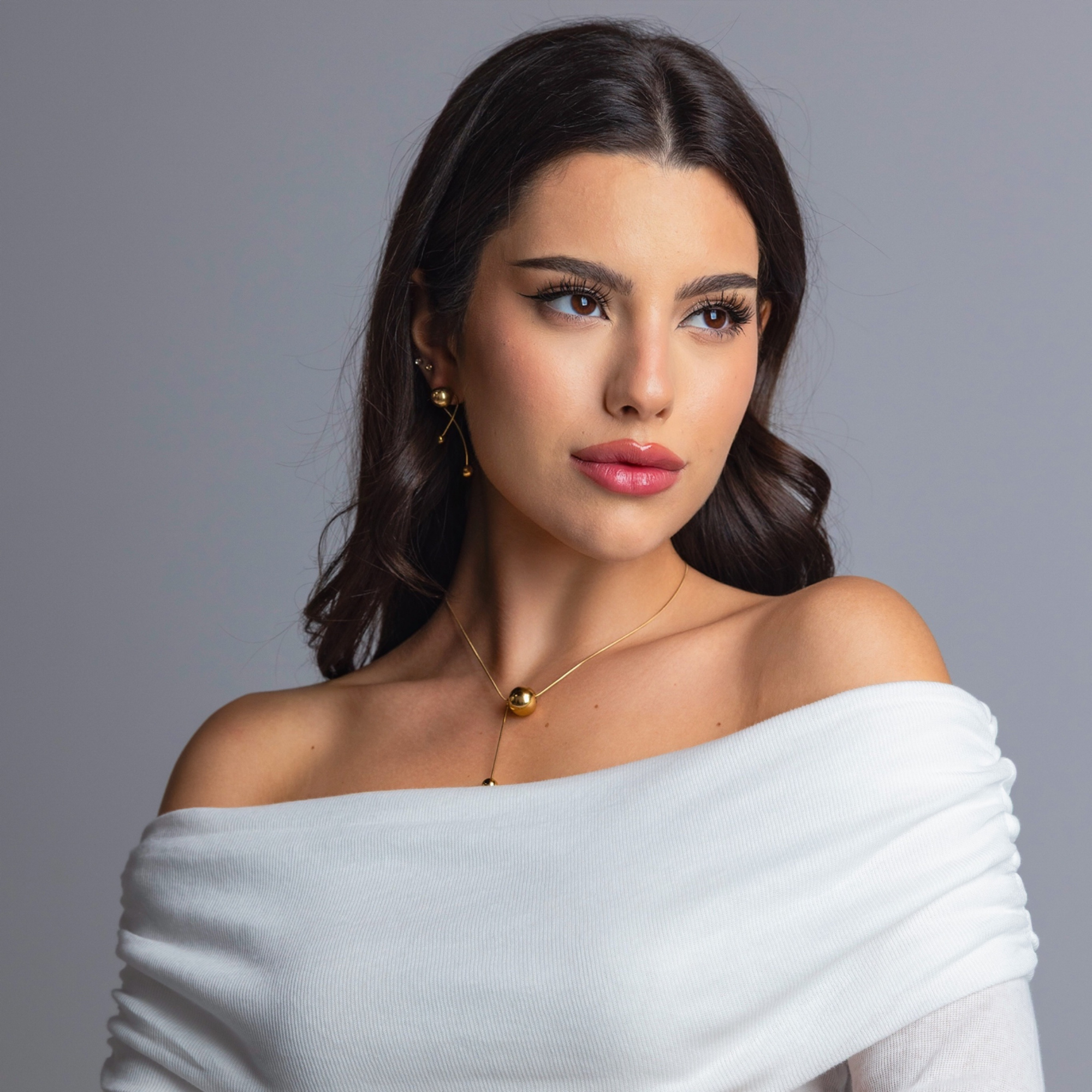 ELAI modular gold earrings styled with an off-shoulder white top