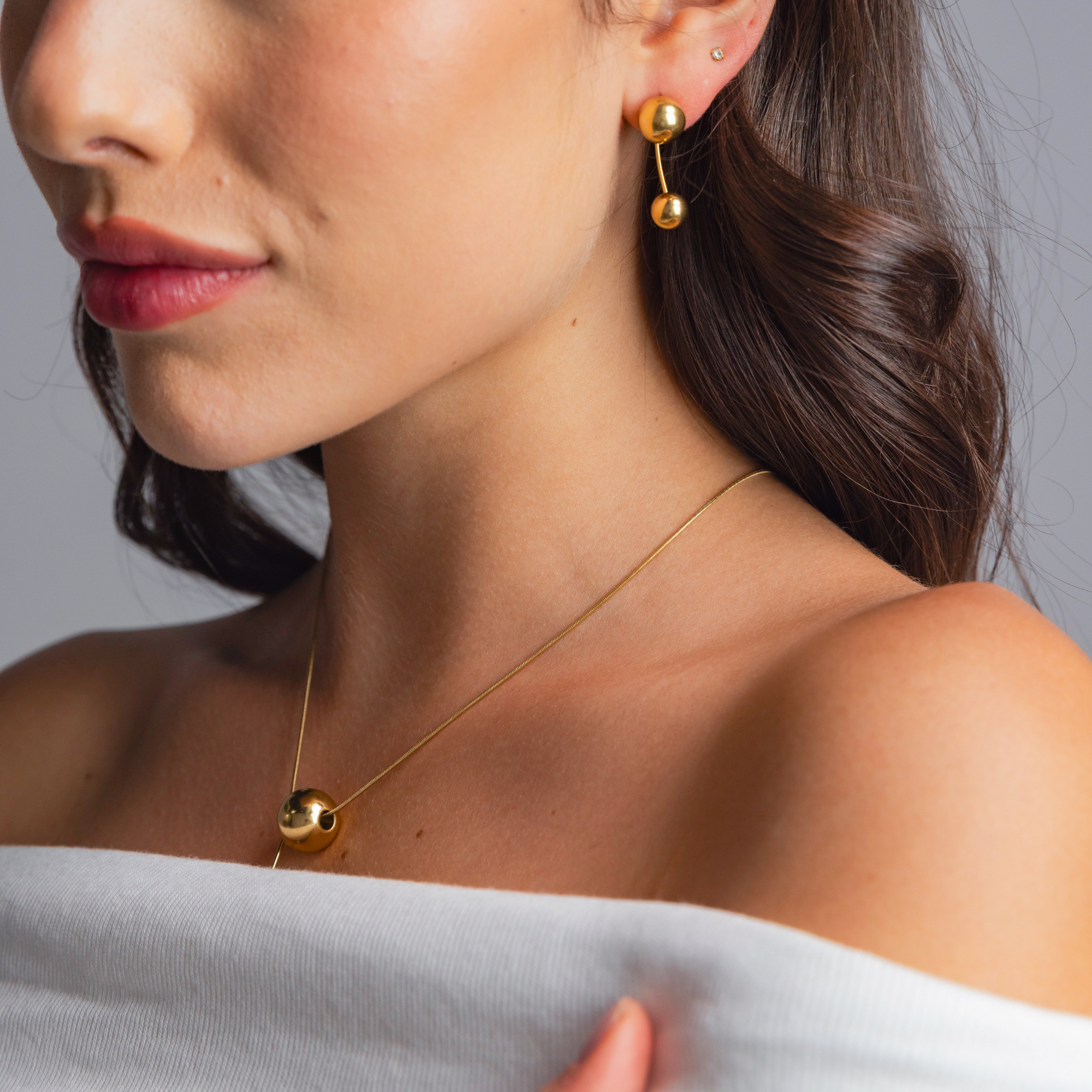Close-up of ELAI gold earrings worn in a minimal two-sphere configuration